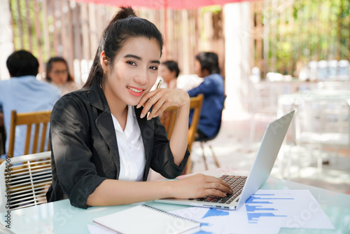 Portrait of smiling pretty young business woman in glasses sitting on workplace
