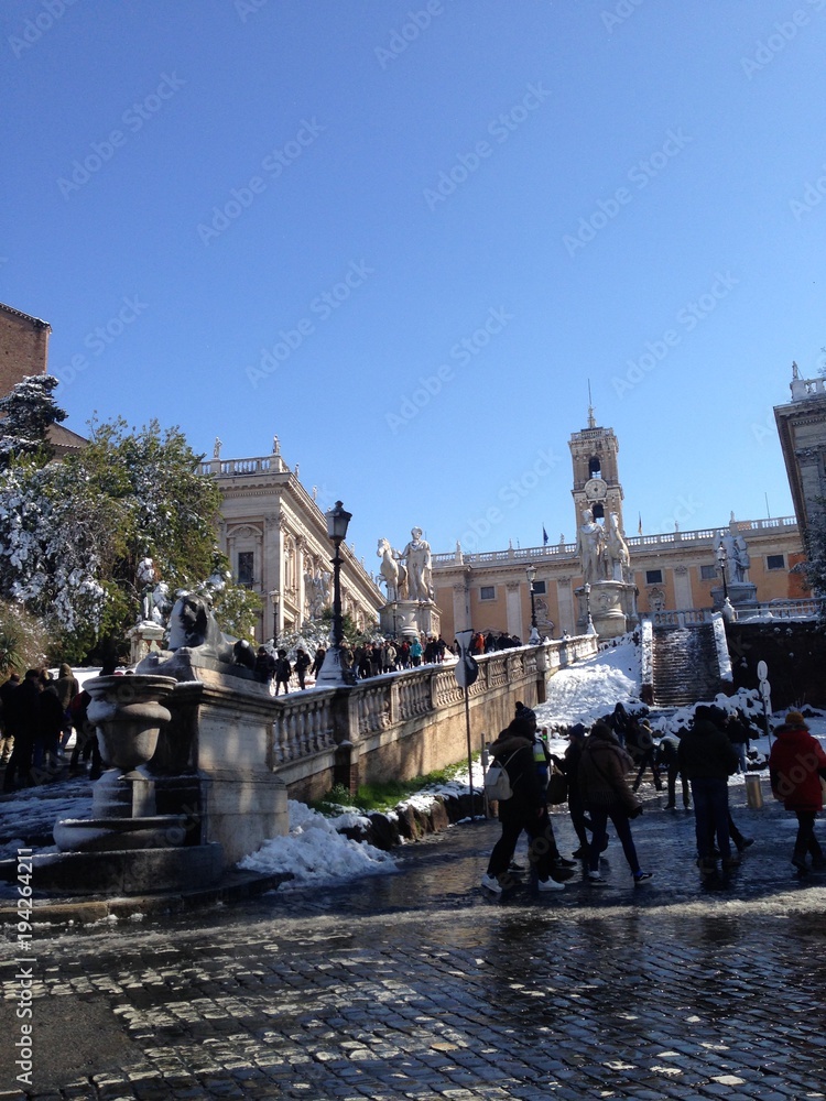 Rome under the snow: view of the Capitoline Hill at the top of the ramp  and people enjoying the city hit by a snow storm