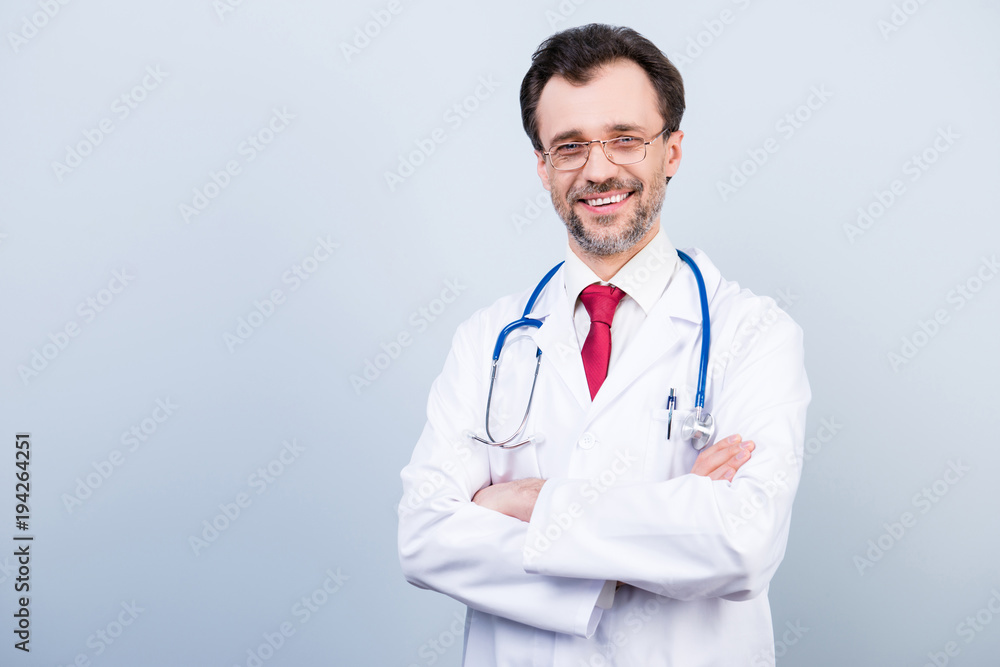 Vertical portrait of excited cheerful qualified expert specialist bearded experienced doctor wearing red tie classic white coat standing with folded arms isolated on gray background copyspace