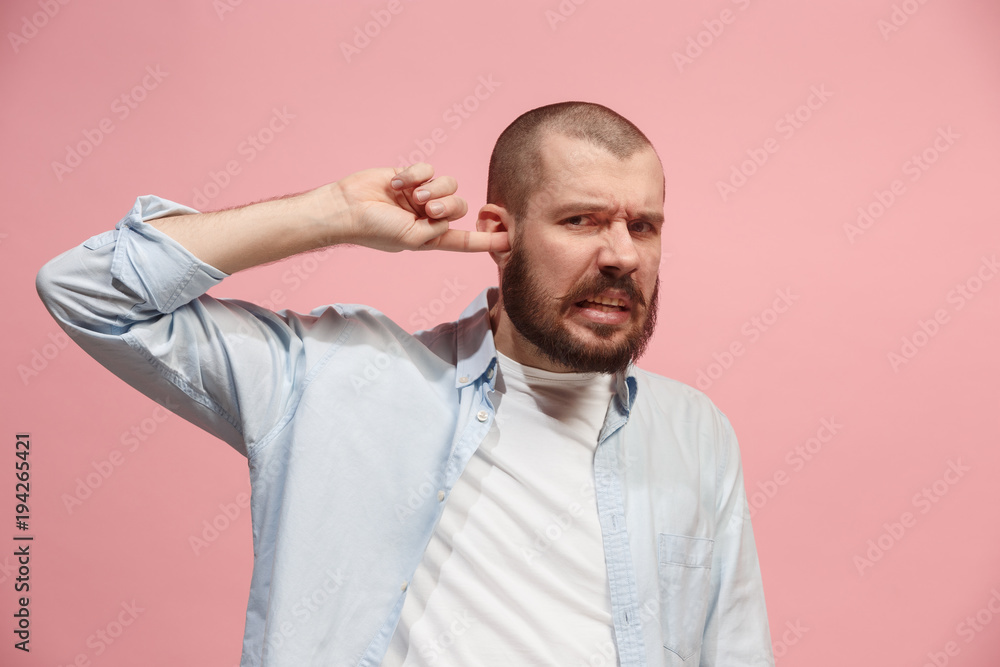 Obraz premium The Ear ache. The sad man with headache or pain on a pink studio background.