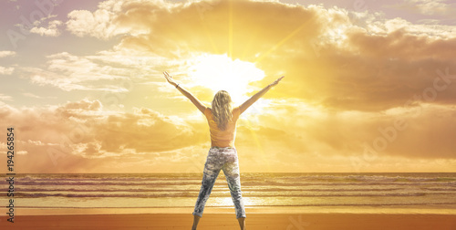 Frau mit ausgebreiteten Armen am Meer