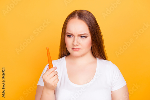 Young woman glaring at a carrot