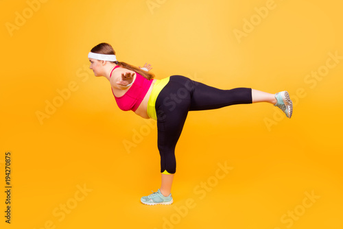 Young woman doing warrior yoga pose on mat at home