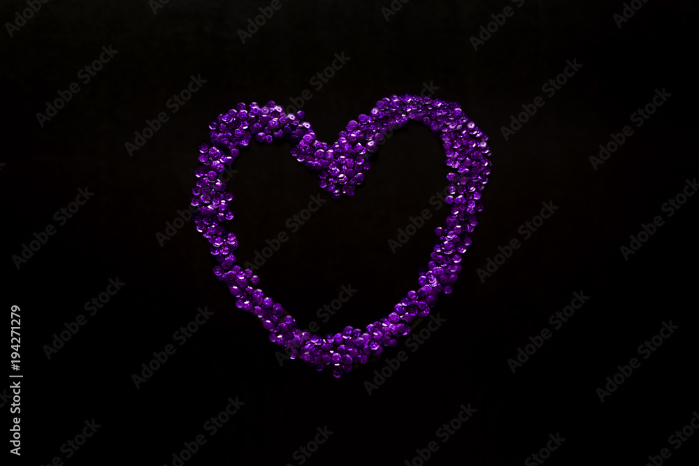 UV paetki scattered in the shape of the heart on a black background.  The decor for the party.