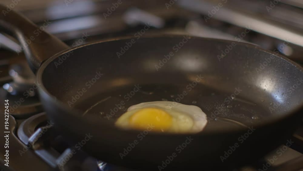A single egg being cracked into a pan and frying. A single egg being cracked into a pan and frying.