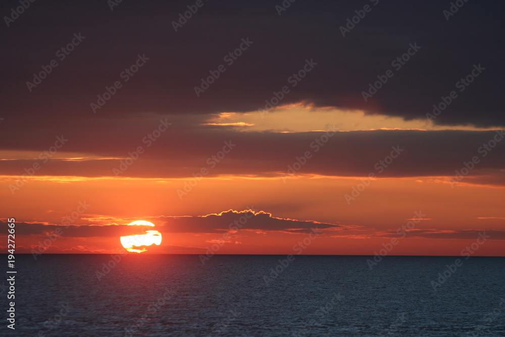 Obraz premium Sonnenuntergang mit Wolken am Meer - Oranger Himmel