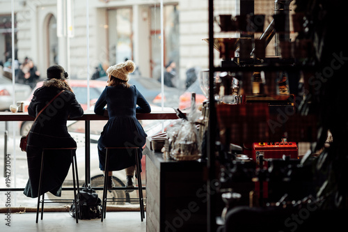 Canvas Print Two woman sit on the table at coffee place and talk to each other