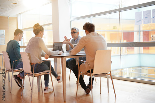 Teacher meeting around table with students