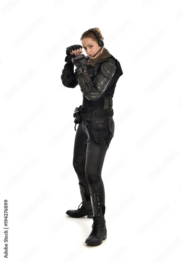 full length portrait of female soldier wearing black tactical armour with arms raised, isolated on white studio background. full length portrait of female soldier wearing black tactical armour with arms raised, isolated on white studio background.