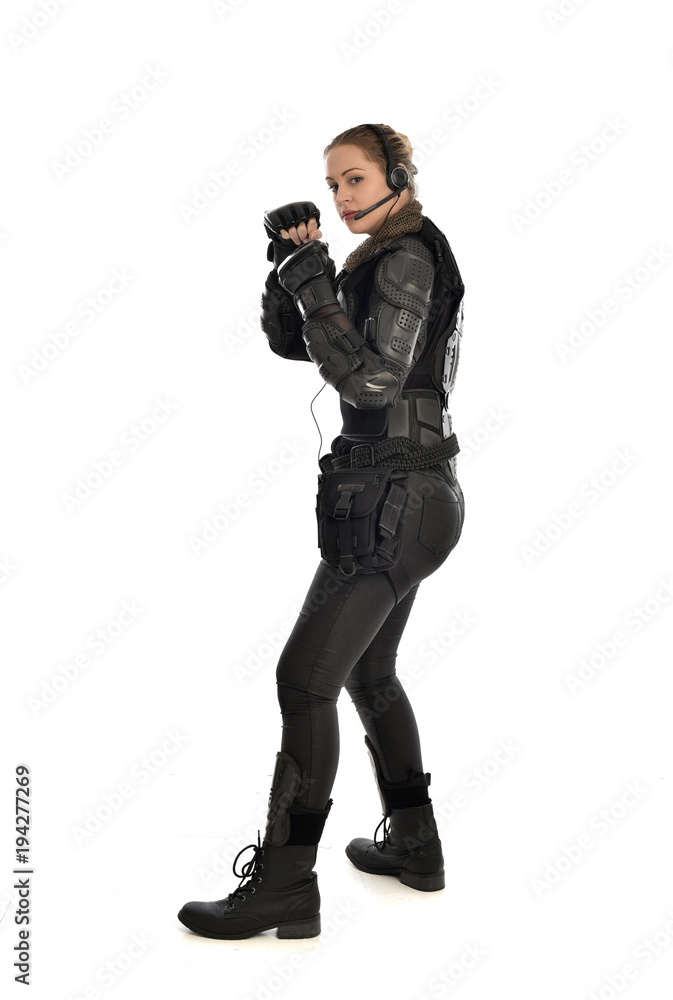 full length portrait of female soldier wearing black tactical armour with arms raised, isolated on white studio background. full length portrait of female soldier wearing black tactical armour with arms raised, isolated on white studio background.