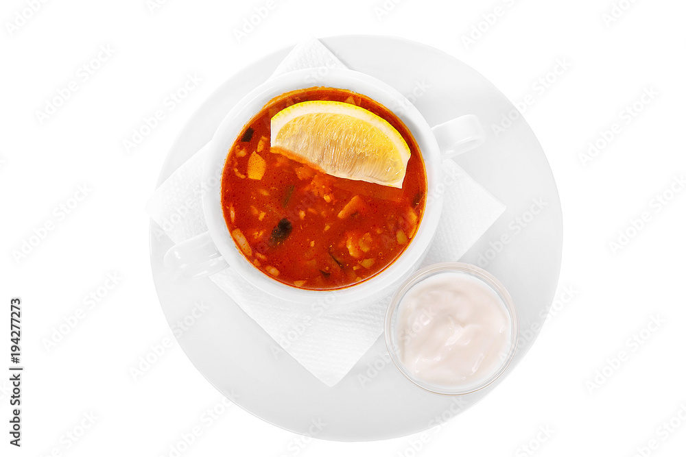 Solyanka, pickle with lemon and sour cream. On a napkin in a white plate isolated white. Serving dishes in a cafe, restaurant, for a menu. View from above Solyanka, pickle with lemon and sour cream. On a napkin in a white plate isolated white. Serving dishes in a cafe, restaurant, for a menu. View from above