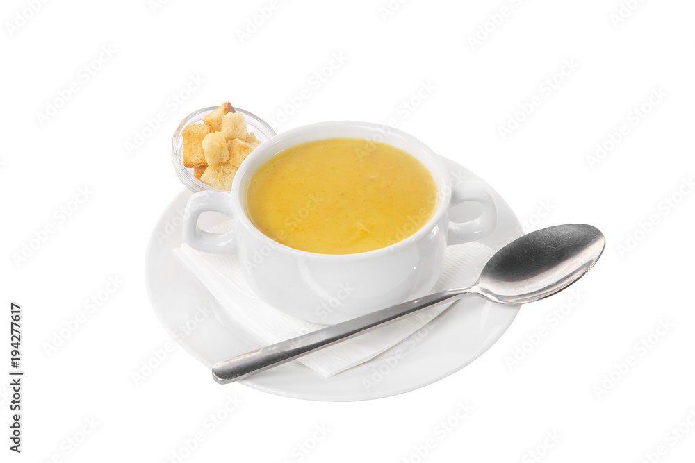 Soup puree, cream soup yellow with crackers, dry bread and a spoon. On a napkin in a white plate isolated white. Serving dishes in a cafe, restaurant, for a menu. Side view Soup puree, cream soup yellow with crackers, dry bread and a spoon. On a napkin in a white plate isolated white. Serving dishes in a cafe, restaurant, for a menu. Side view