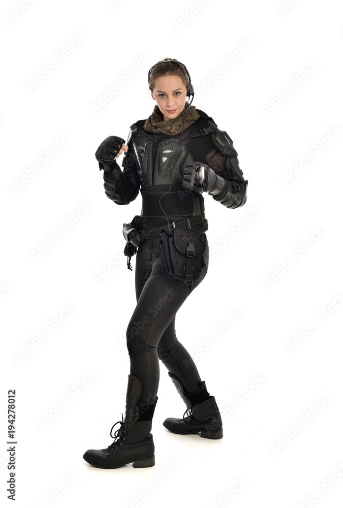 full length portrait of female  soldier wearing black  tactical armour with arms raised, isolated on white studio background.