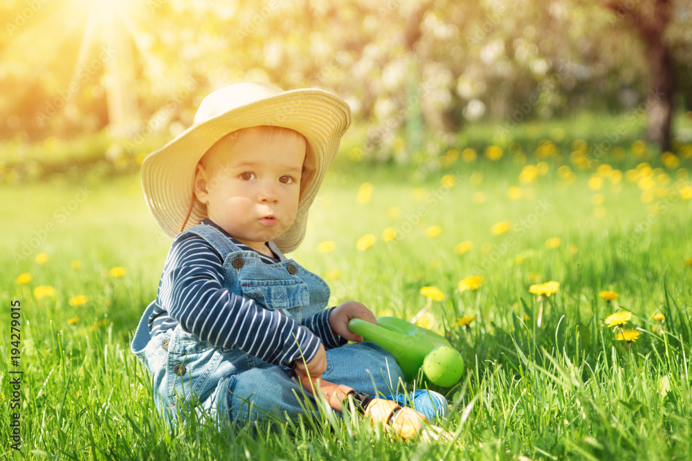 Baby boy sitting on the grass with dandelion flowers in the garden Baby boy sitting on the grass with dandelion flowers in the garden