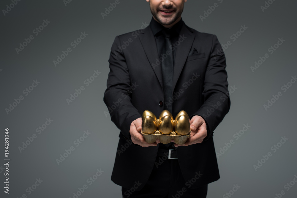 Cropped view of stylish man with golden eggs isolated on grey, easter concept Cropped view of stylish man with golden eggs isolated on grey, easter concept