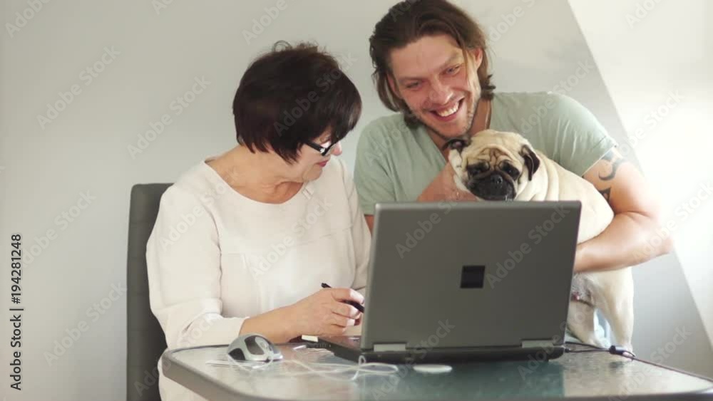 Mother and son communicate in Skype with relatives. Call the dog and show it to the camera. Jokingly waving the dog's paw Mother and son communicate in Skype with relatives. Call the dog and show it to the camera. Jokingly waving the dog's paw