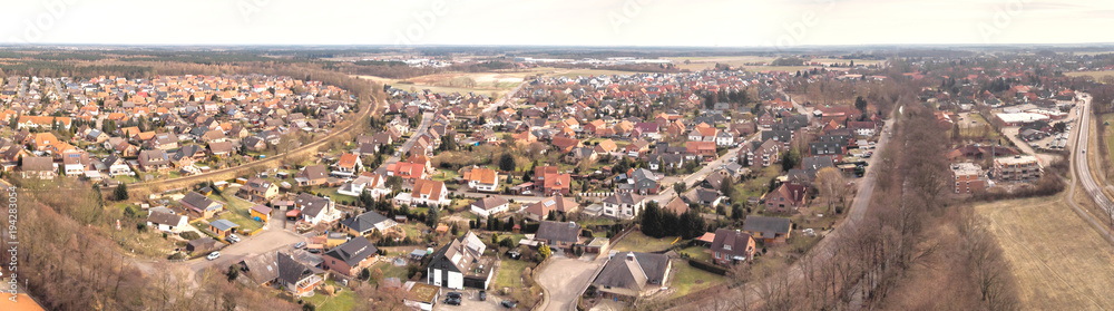 Composite panorama of aerial photographs and aerial photos of a small village in the heath in Northern Germany with meadows, fields and houses, above the roofs.
