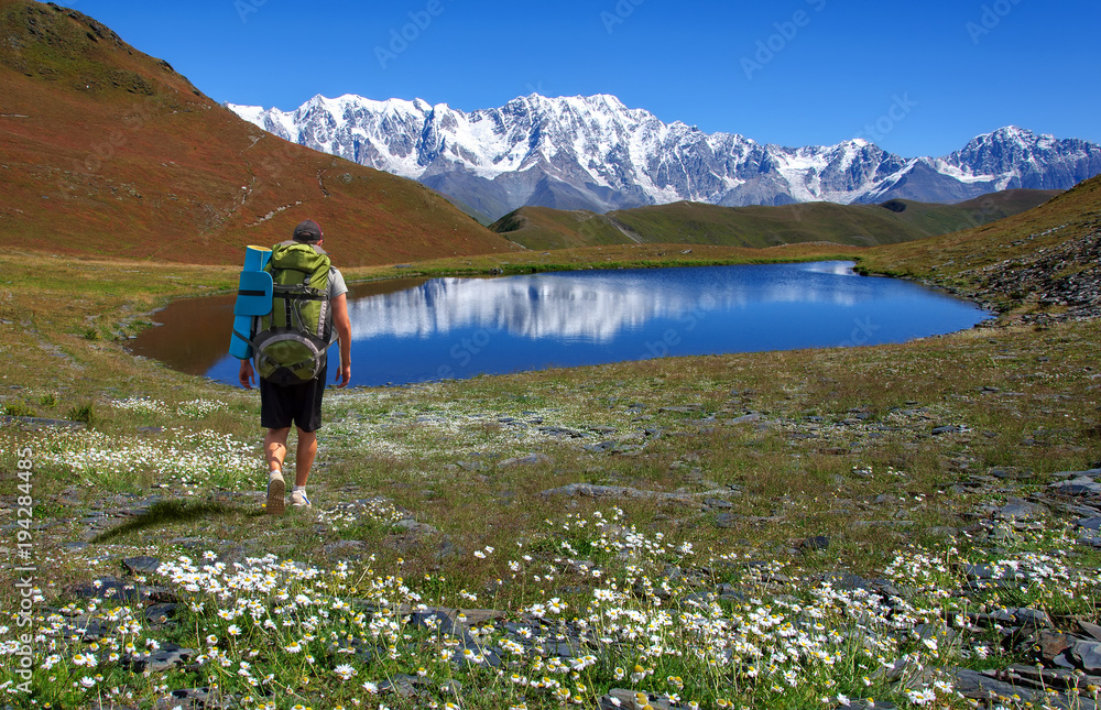Man with backpack posing at lake in Caucasus mountains in Georgia