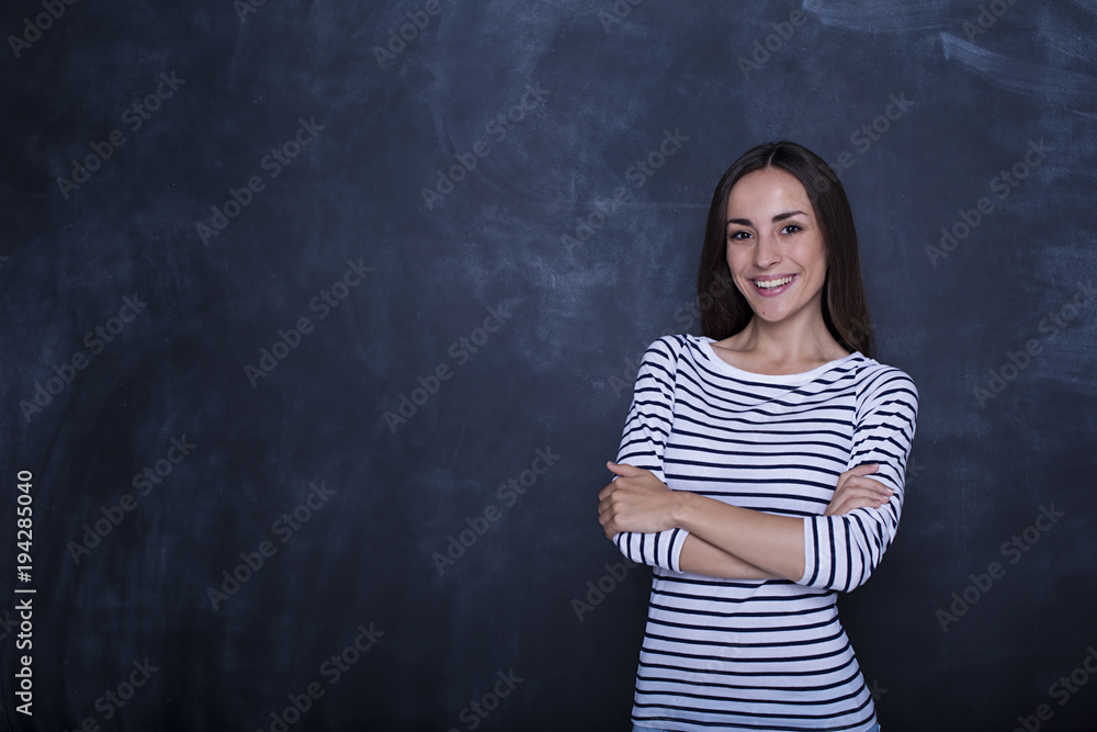 Attractive happy thoughtful woman looking on camera with crossed hands near copyspace over black background