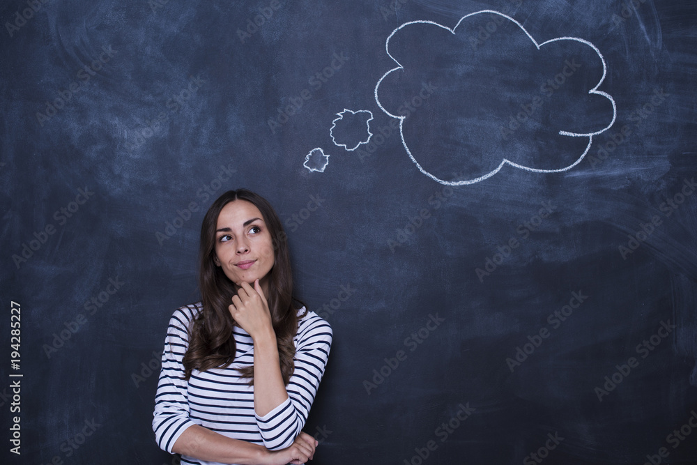 What should I buy? Young beautiful woman at the board thinking about the goods that need to buy