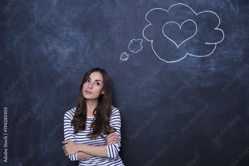 Happy young woman dreaming of love on the background of a blackboard Happy young woman dreaming of love on the background of a blackboard