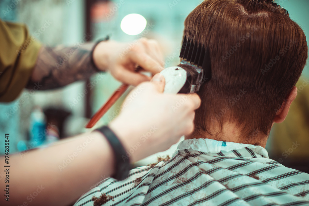 Fototapeta premium Men's haircut in barbershop. Hair care. Tinted photo. Soft focus.