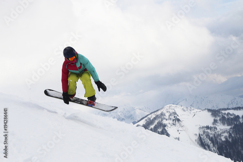 The girl on snowboard jumps in the cloudy mountains