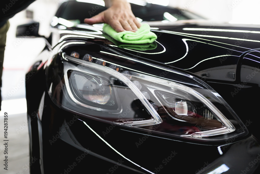 A man cleaning car with microfiber cloth, car detailing (or valeting) concept. Selective focus. 