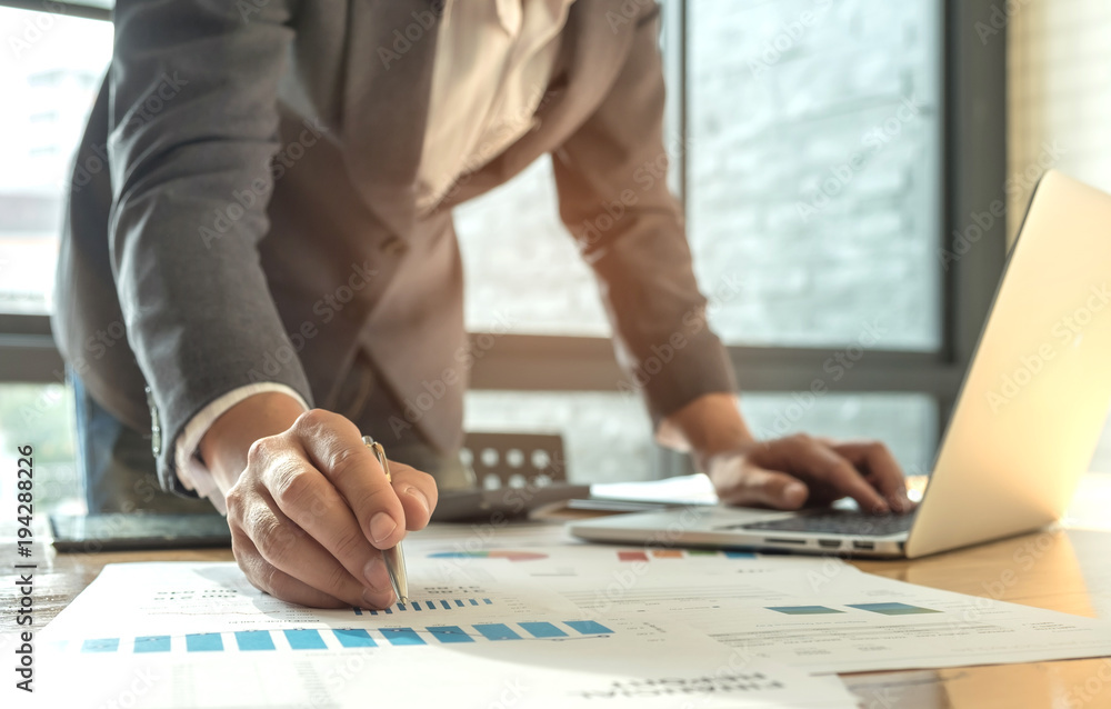 Business concepts,Men wearing suits are using a pen pointing on graph and another hand use laptop. Business concepts,Men wearing suits are using a pen pointing on graph and another hand use laptop.