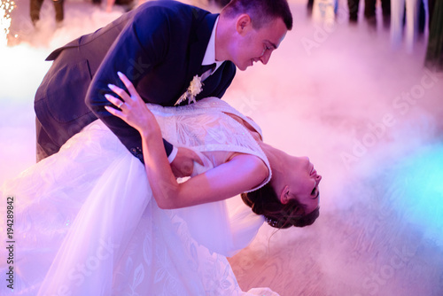 Groom whirls bride while they dance in a smoke for the first time