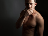 Handsome athletic guy with a naked torso on a black background