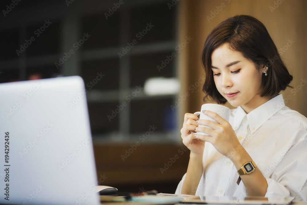 Businesswoman working on laptop while drinking coffee in the office Businesswoman working on laptop while drinking coffee in the office
