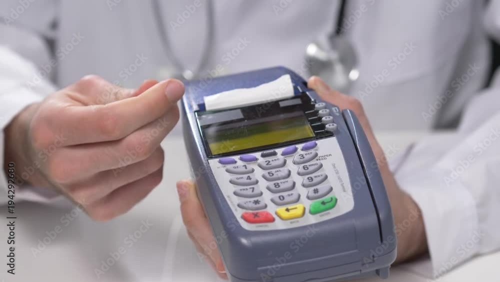 Doctor holding a credit card terminal to the patient. Doctor holding a credit card terminal to the patient.