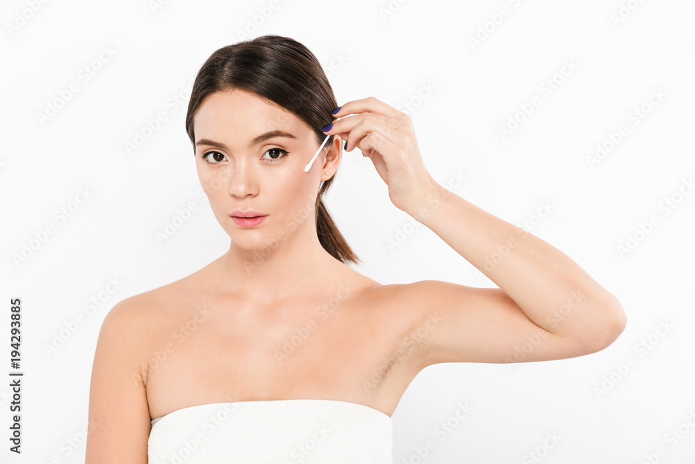 Young calm woman using cotton stick to clean face isolated over white Young calm woman using cotton stick to clean face isolated over white