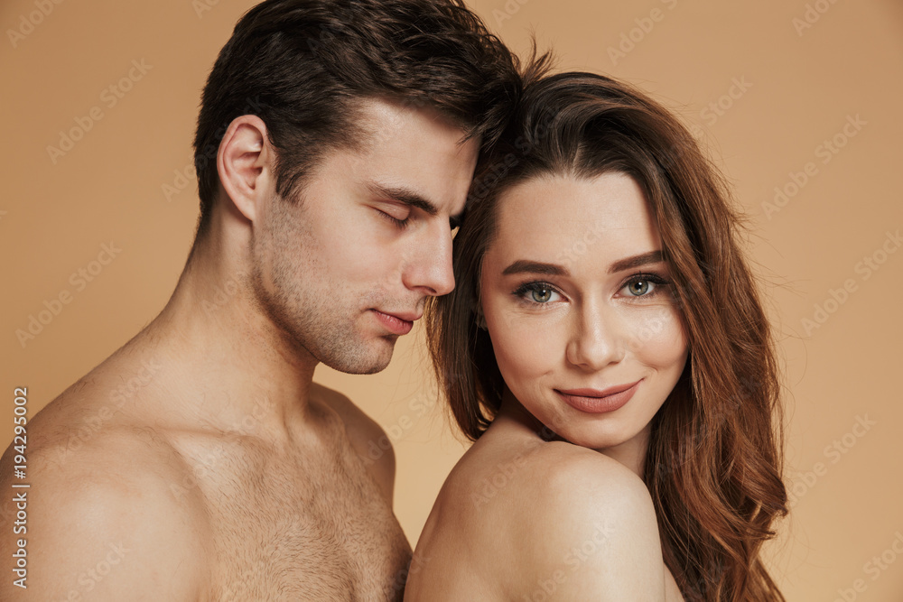 Smiling lady looking camera and smiling while standing near her shirtless man isolated Smiling lady looking camera and smiling while standing near her shirtless man isolated