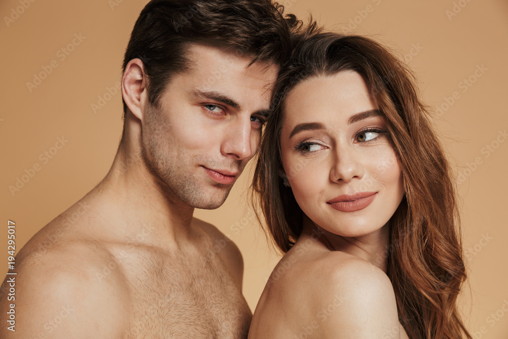 Confident handsome man looking camera while hugging his shirtless woman isolated Confident handsome man looking camera while hugging his shirtless woman isolated