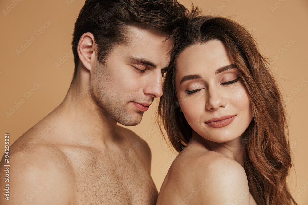 Portrait of beautiful pleased lovers standing isolated over beige Portrait of beautiful pleased lovers standing isolated over beige