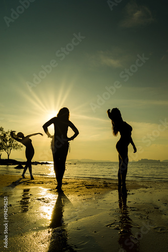 Silhouette of three girls on the beach at sunset
