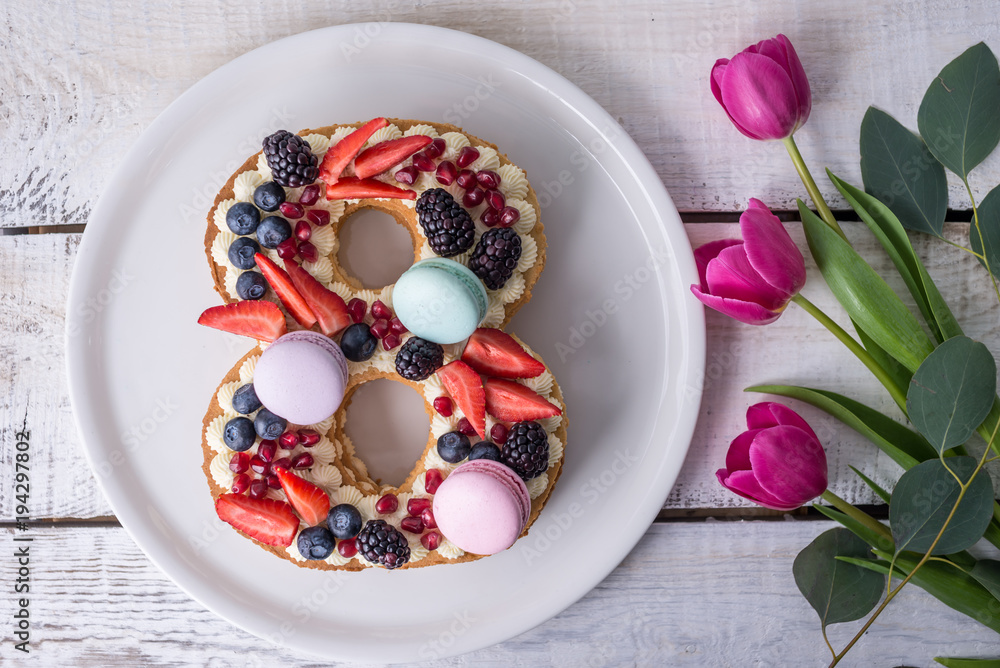 Cake in shape of number 8 decorated with berries and flowers tulips. Dessert for women's day on the eighth of March Cake in shape of number 8 decorated with berries and flowers tulips. Dessert for women's day on the eighth of March