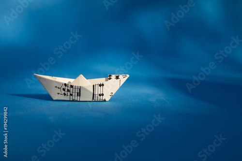Paper boat made of musical score sheet in blue background