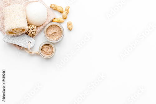 Natural cosmetics for skin care. Body scrub with peanut. White background top view copy space