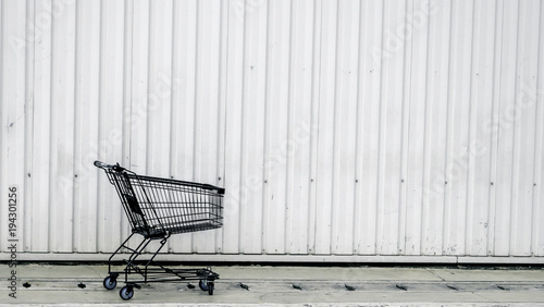 Shopping trolley on a white contrainer. Black cart for background.