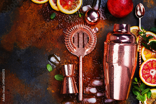 Bar accessories, drink tools and cocktail ingredients on rusty stone table. Flat lay style photo