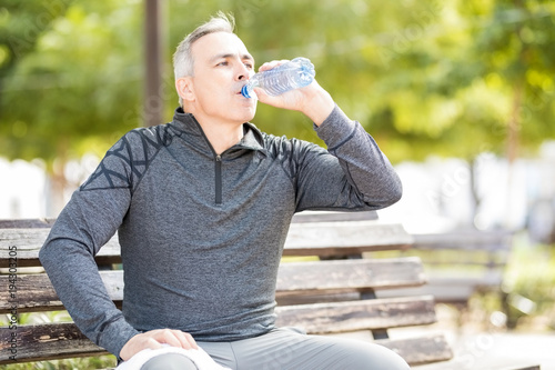 Mature man drinking water to refresh after a workout