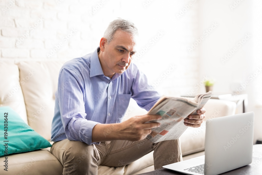 Good looking man reading a newspaper at home Good looking man reading a newspaper at home