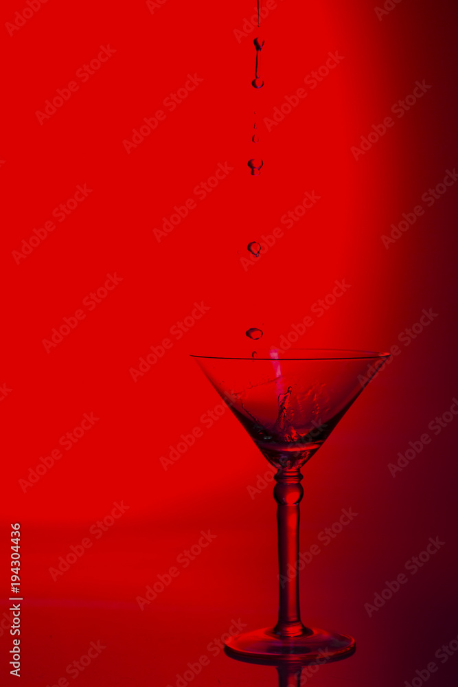 Martini glass high key photo in studio with red tint and water plash Martini glass high key photo in studio with red tint and water plash