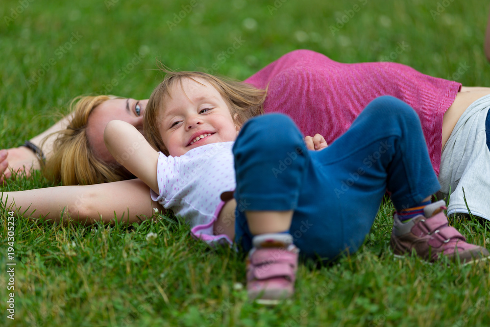 little girl lying on the grass with her mother little girl lying on the grass with her mother