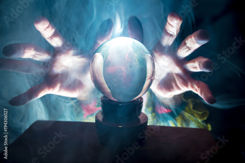 A fortune teller works in a dark room with a crystal ball
