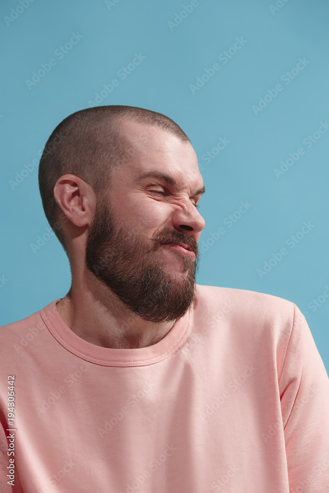 Young man with disgusted expression repulsing something, isolated on the blue Young man with disgusted expression repulsing something, isolated on the blue