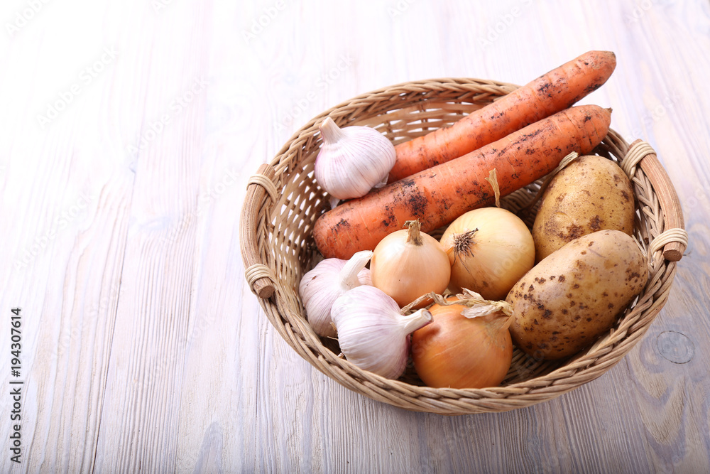 Basket with vegetables. Carrot. potato and garlic on wood background. Natural food with space for text Basket with vegetables. Carrot. potato and garlic on wood background. Natural food with space for text